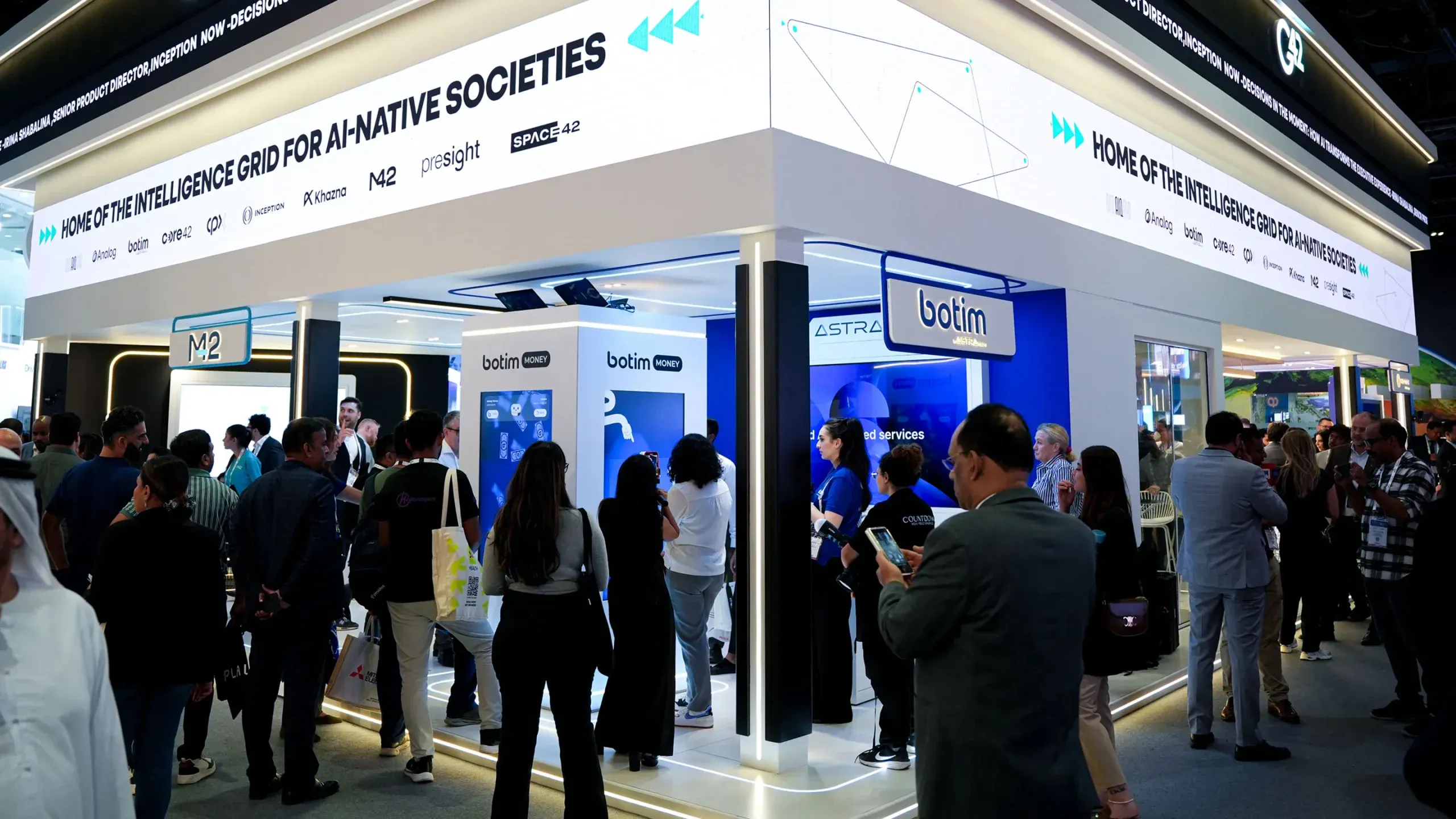 Wide view of the botim booth at GITEX Global with a crowd around the game screens.