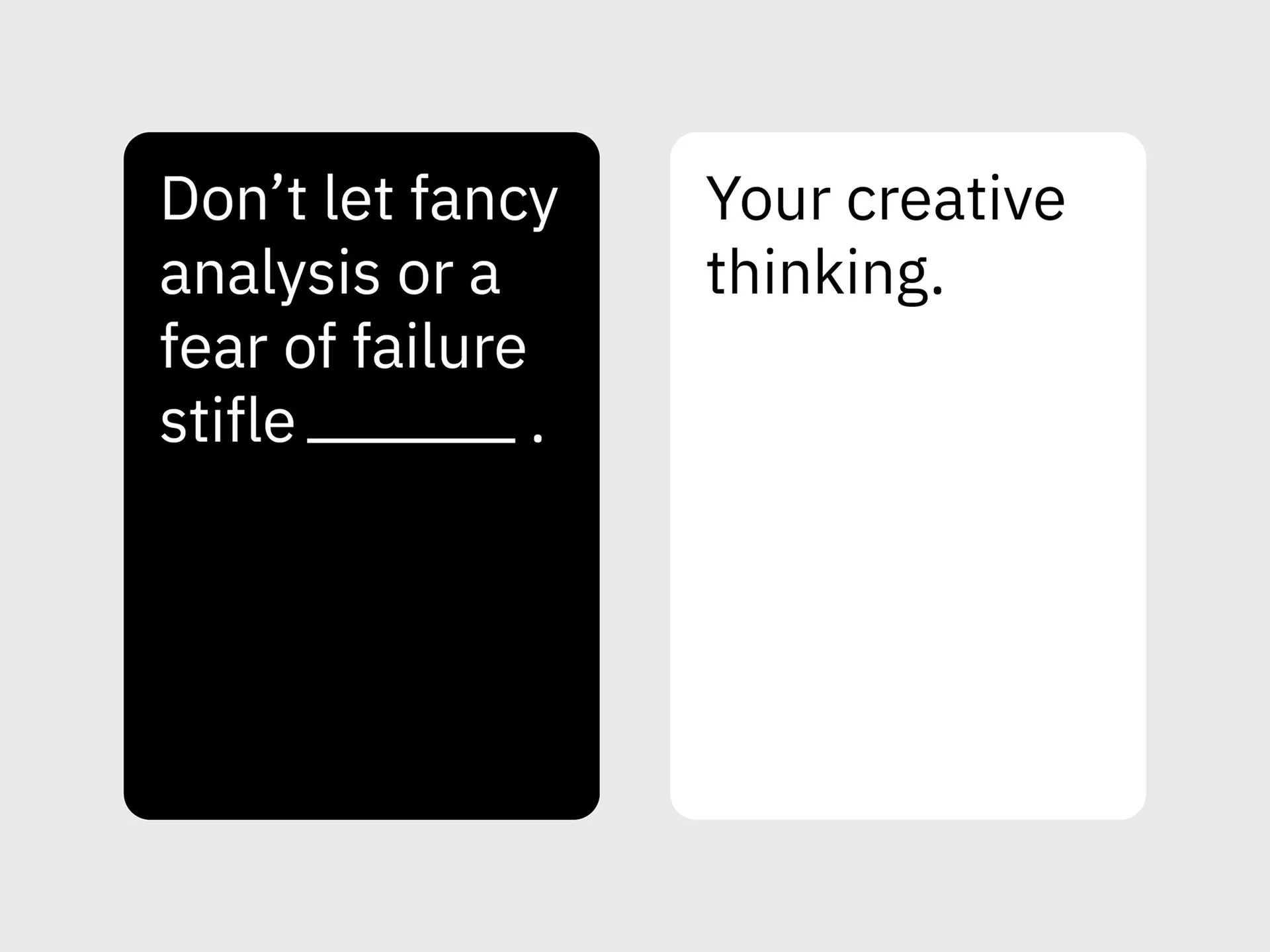 Two playing cards side-by-side. The black card on the left reads, "Don’t let fancy analysis or a fear of failure stifle _______." The white card on the right reads, "Your creative thinking."
