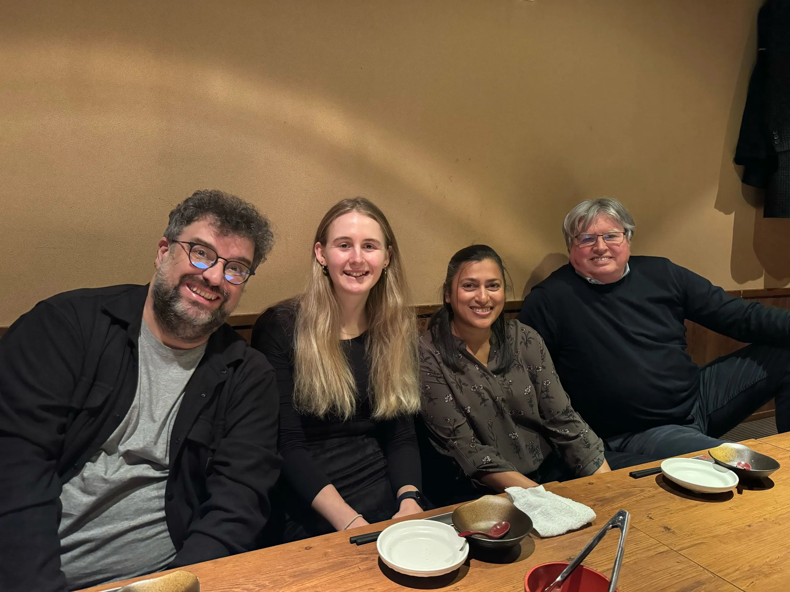 Four colleagues smile for the camera around a low table in a restaurant in Tokyo.