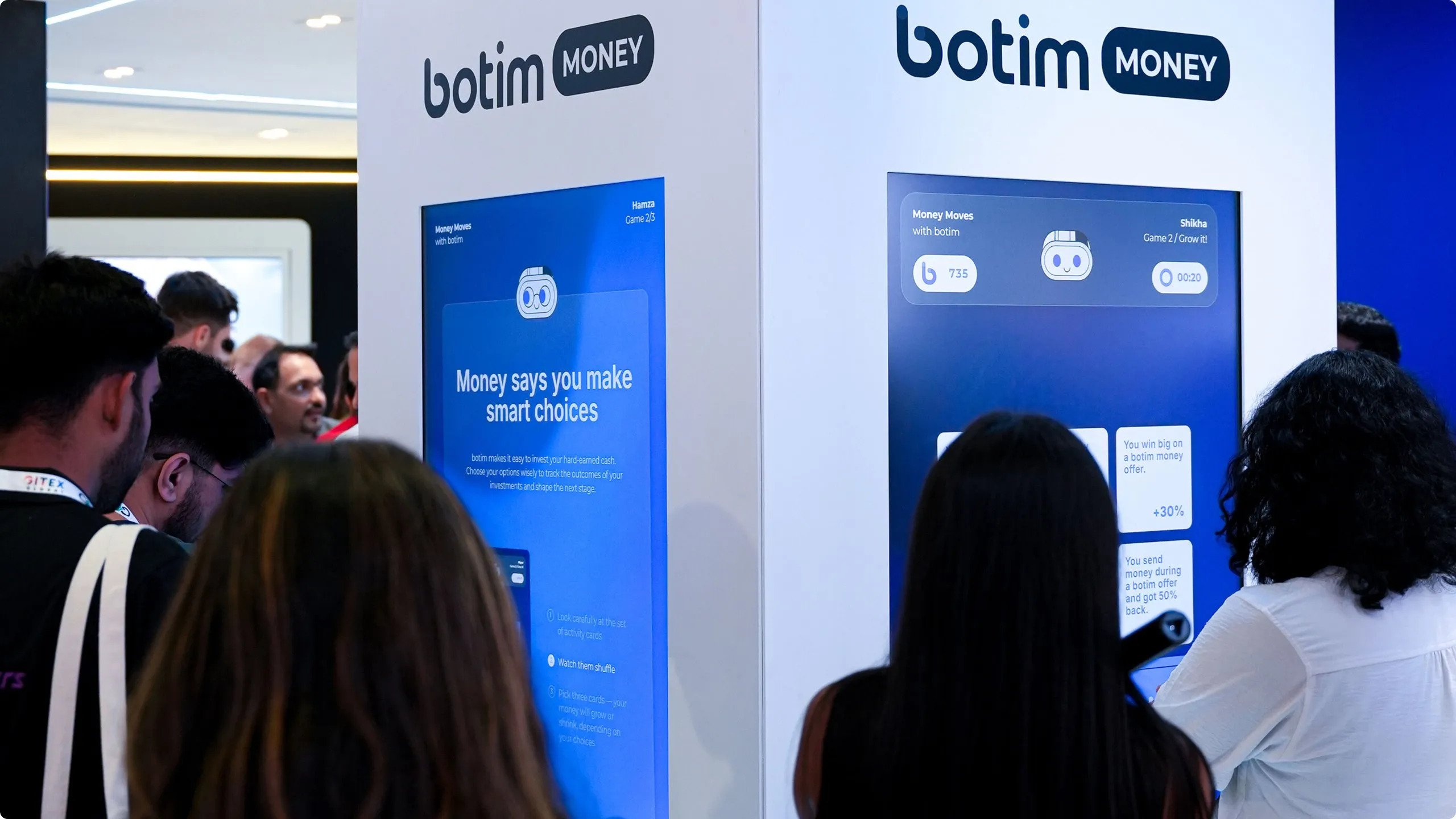 Visitors queue at two tall screens on the botim Money stand, one reading 'Money says you make smart choices'.