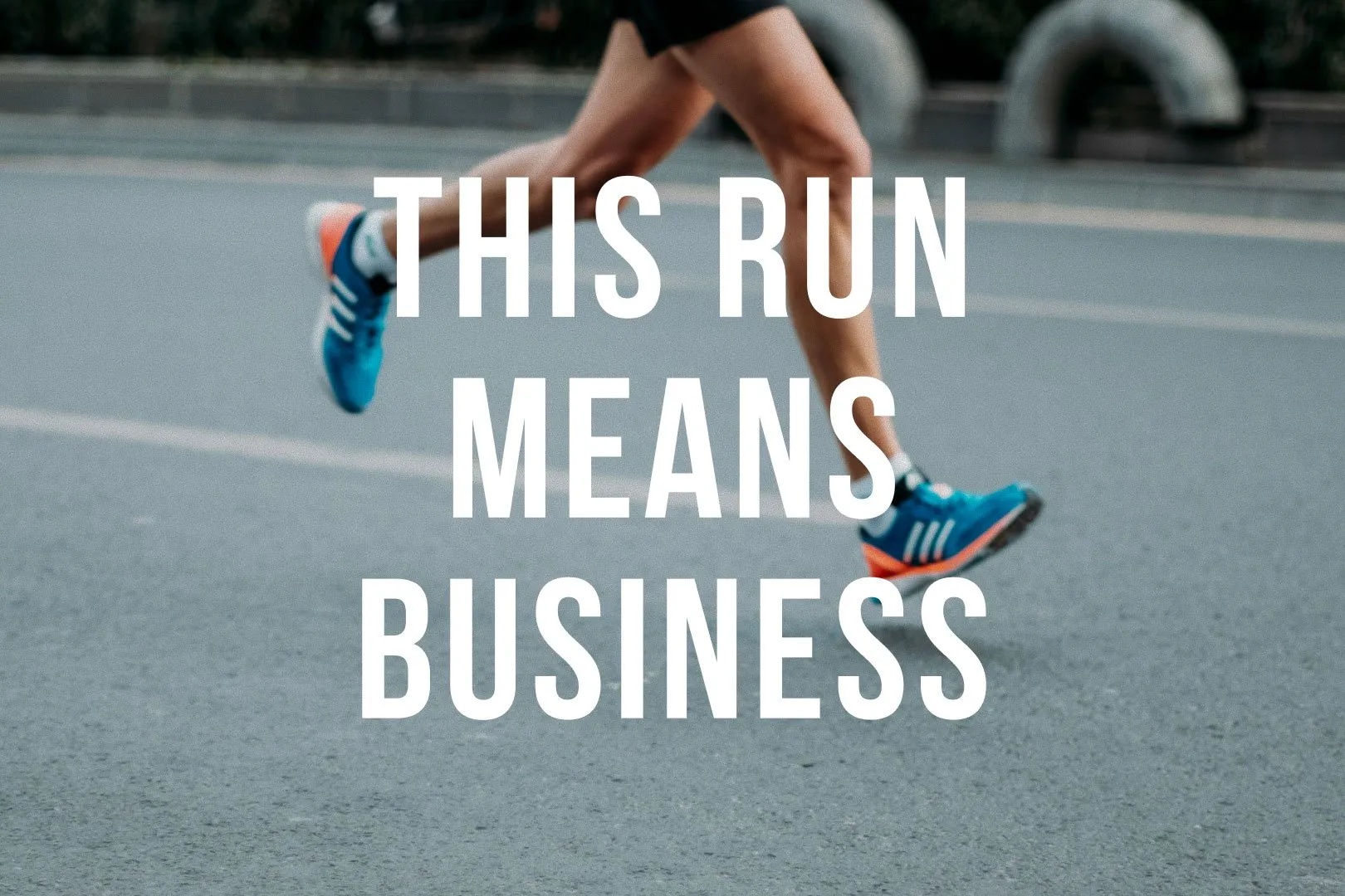 Close-up of a runner's legs in blue and orange sneakers mid-stride on an asphalt road, overlaid with large white text reading THIS RUN MEANS BUSINESS.